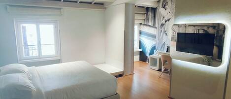 Une chambre moderne avec un lit, une télévision et un bureau.