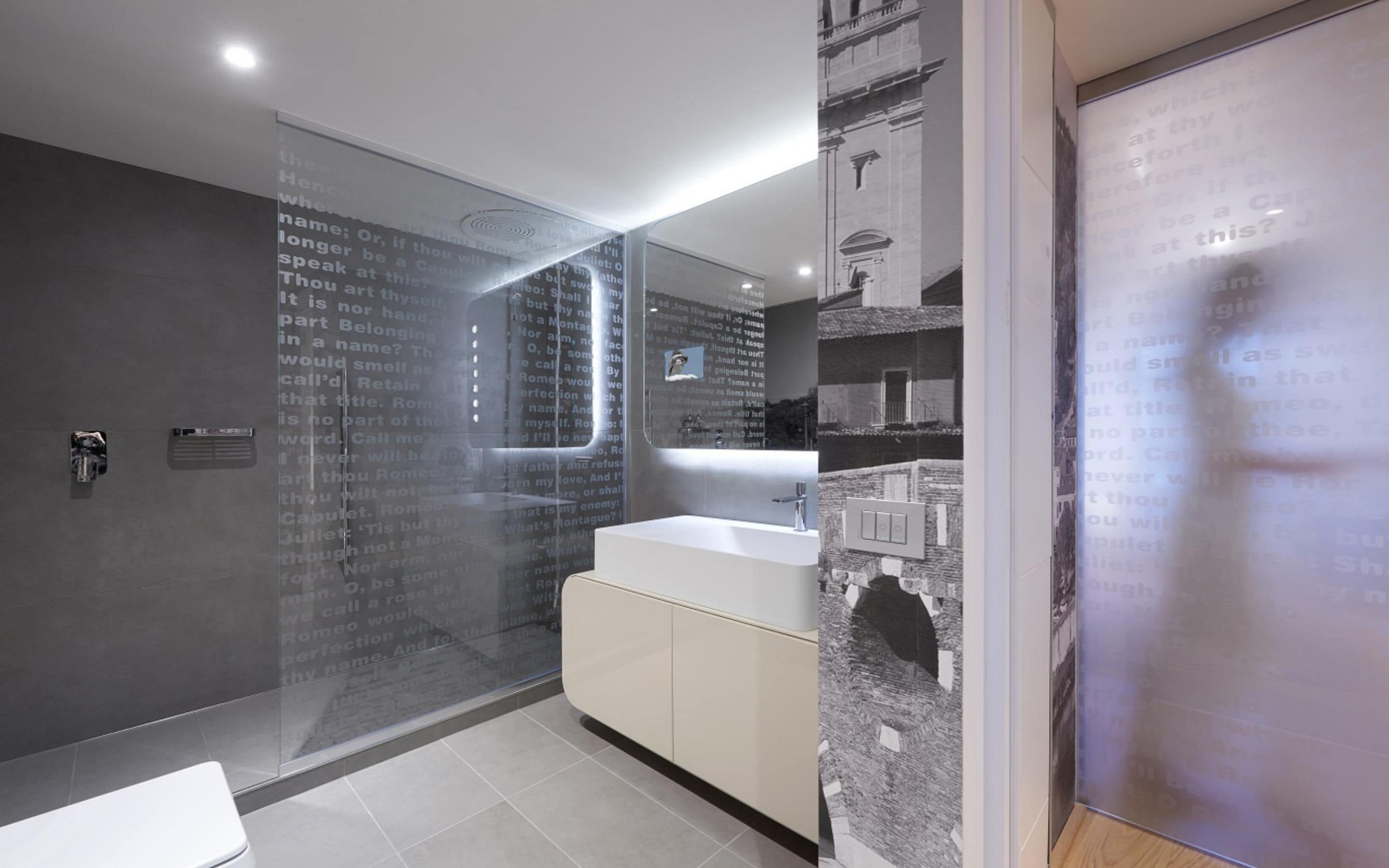 A modern bathroom with a glass shower enclosure, a white sink, and a large mirror.