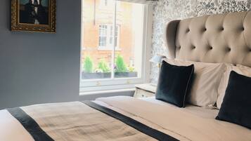 Een slaapkamer met een groot bed, een raam met uitzicht op een gebouw en een ingelijst schilderij aan de muur.