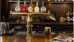 Un bar con un sistema di erogazione delle bevine, scaffali pieni di bottiglie di liquori e un bicchiere di birra sul bancone.