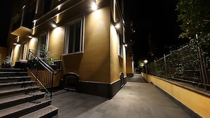 A nighttime view of a building with a staircase leading to a door, a small window, and a metal railing. - Villa San Martino (Naples)