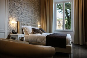 A hotel bedroom with a bed, bedside table, lamp, and a window with curtains. - Villa San Martino (Naples)