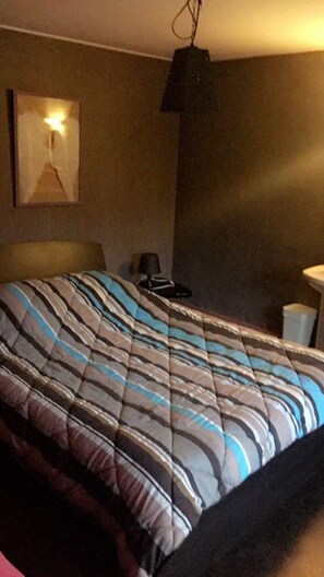 A hotel room with a bed, a bedside table, a lamp, and a wall-mounted light fixture. - Hotel Restaurant L'Angelus (Saulxures-sur-Moselotte)