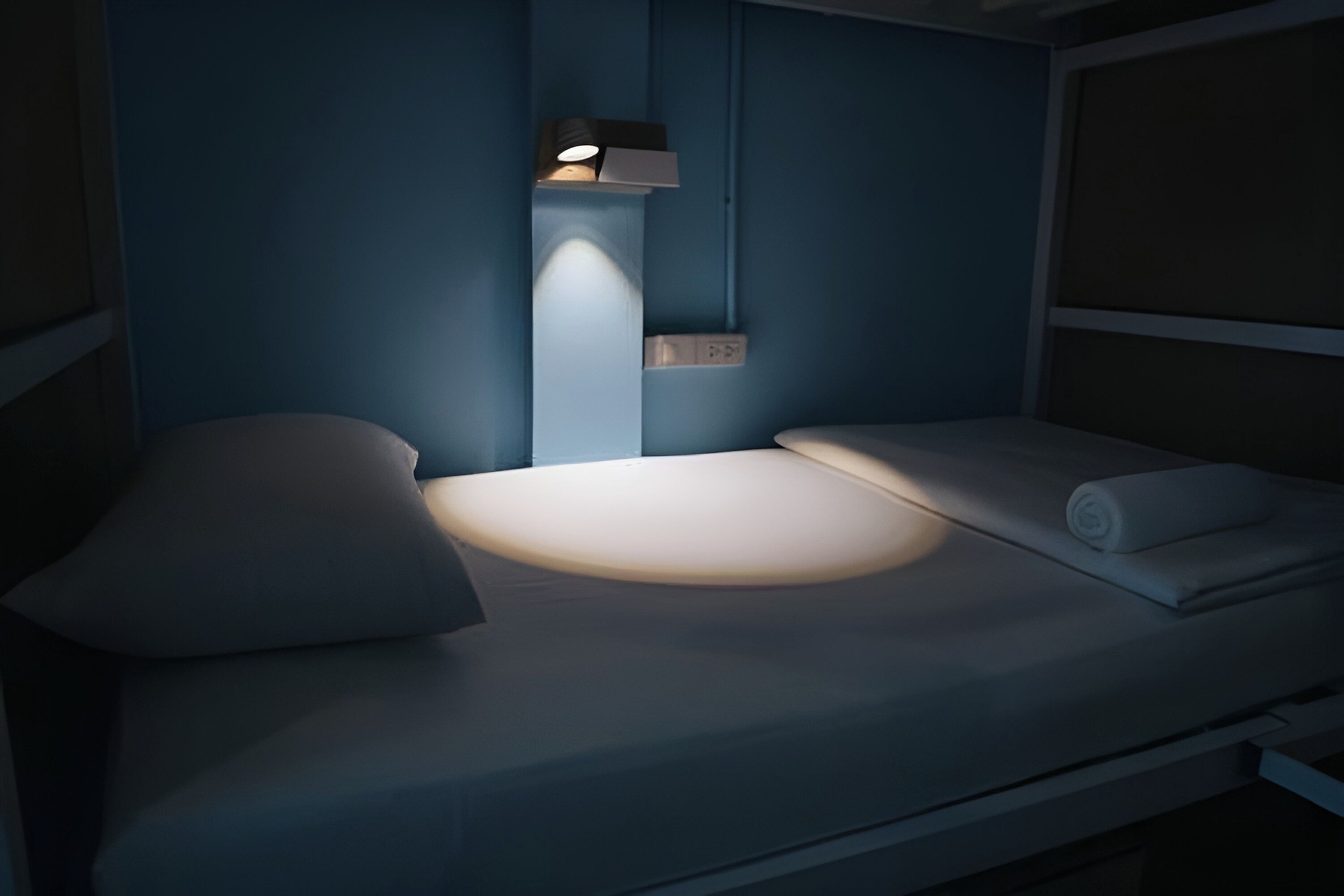 A single bed with a headboard, a bedside table, and a wall-mounted light fixture.