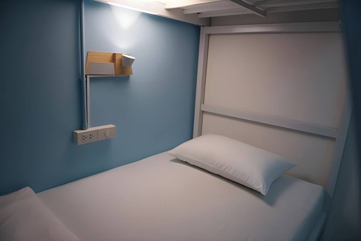 A single bed with white bedding in a room with blue walls and a white headboard.