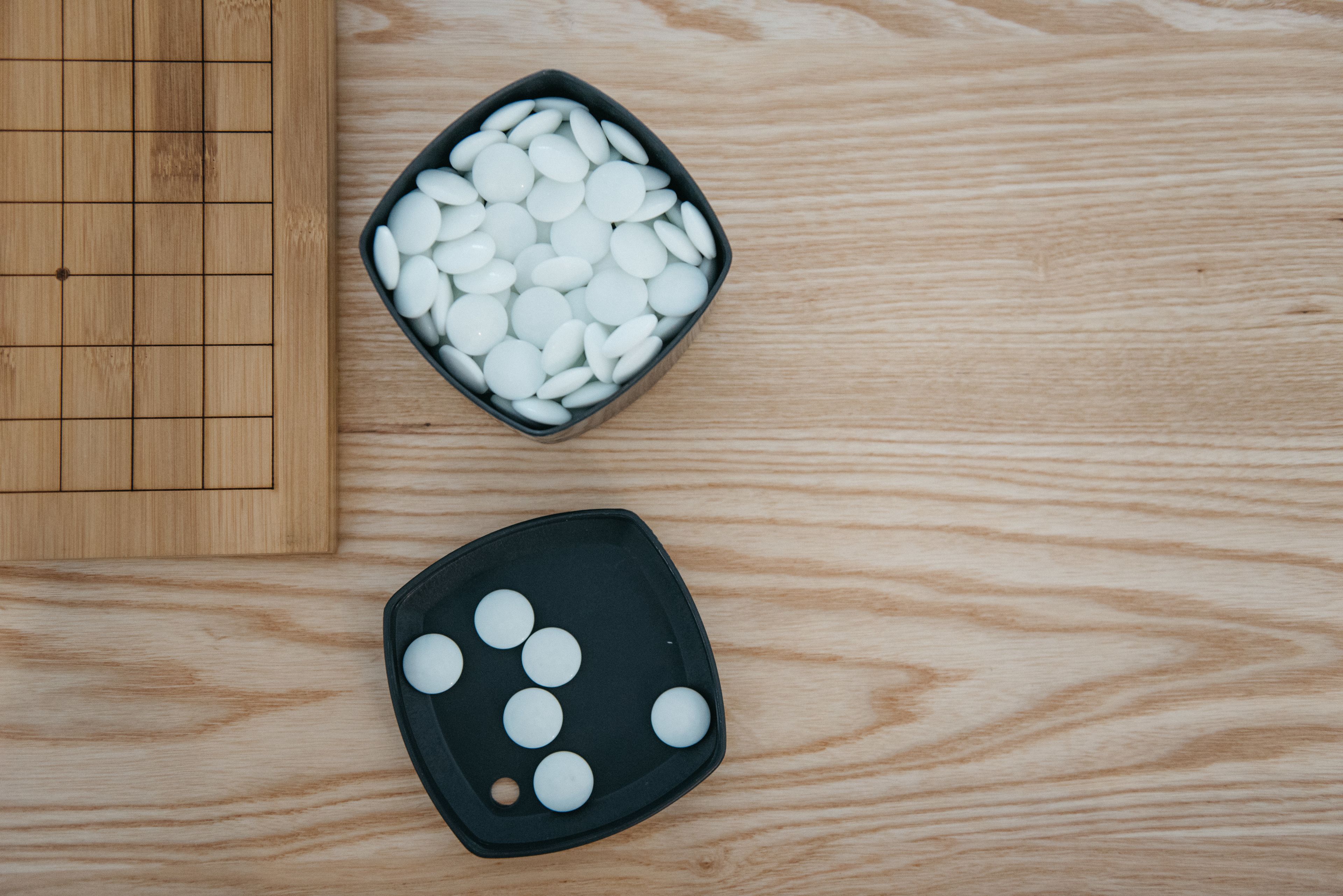 Une table en bois sur laquelle se trouve un plateau noir contenant des objets sphériques blancs, ainsi qu’un plus petit plateau noir contenant moins d’objets sphériques blancs.
