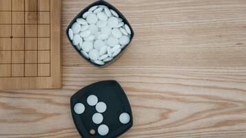 Une table en bois sur laquelle se trouve un plateau noir contenant des objets sphériques blancs, ainsi qu’un plus petit plateau noir contenant moins d’objets sphériques blancs.