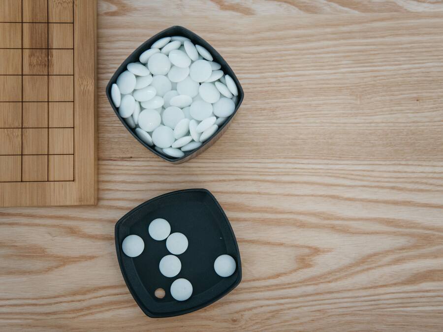 Une table en bois sur laquelle se trouve un plateau noir contenant des objets sphériques blancs, ainsi qu’un plus petit plateau noir contenant moins d’objets sphériques blancs.