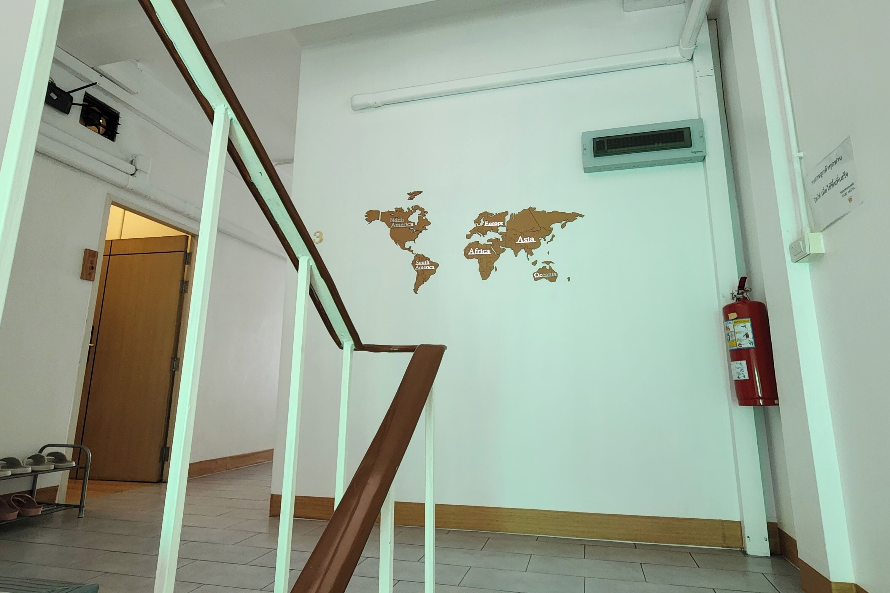 Un pasillo con un mural de un mapa mundial, un extintor y una escalera.