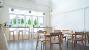 A bright, spacious room with a large window, wooden furniture, and hanging pendant lights. - Ease Hostel (Bangkok)