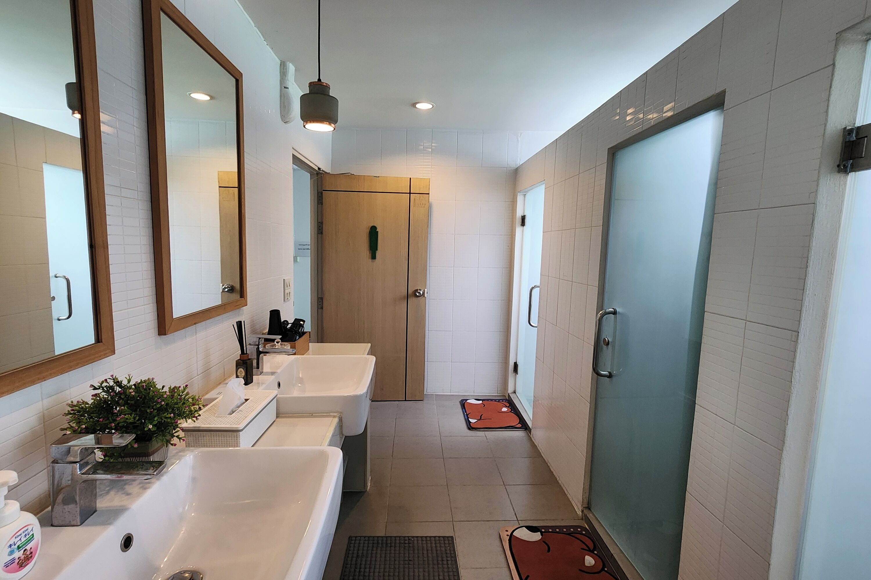A modern bathroom with two sinks, a mirror, and a glass shower door.