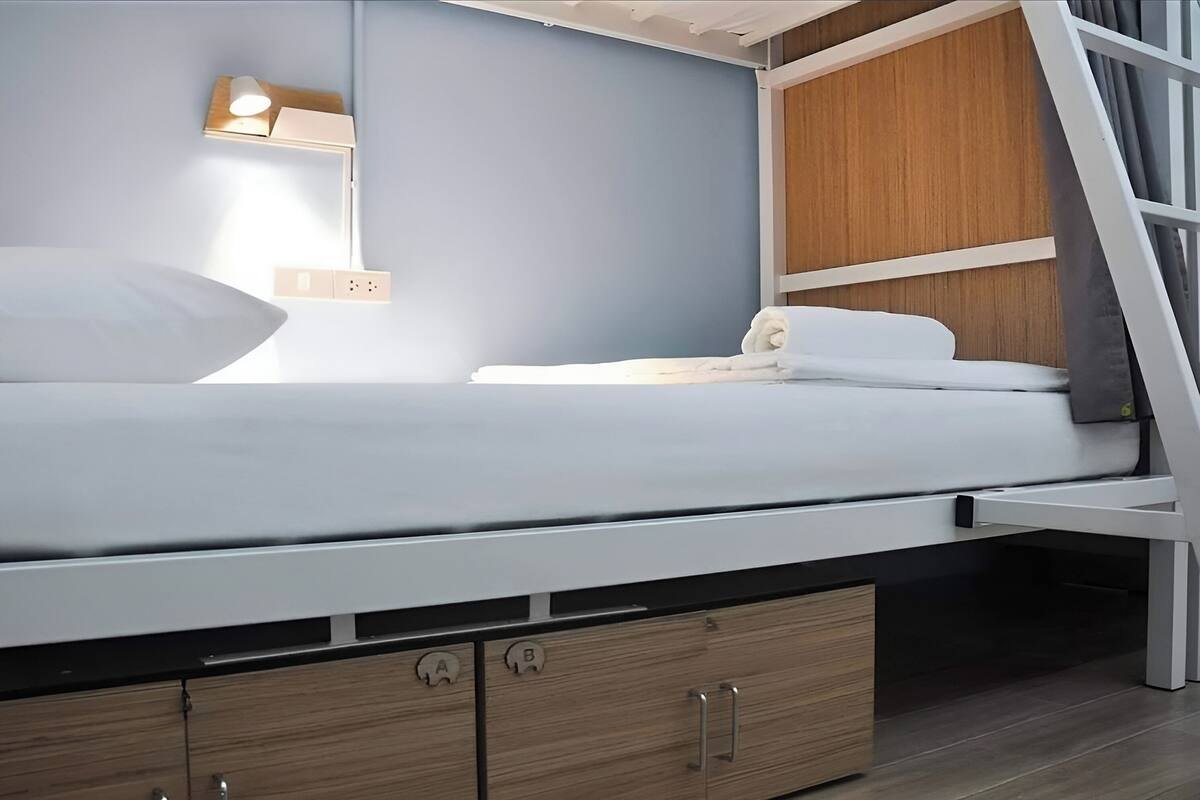 A modern bed with a headboard, a bedside table with a lamp, and a wooden panel wall.