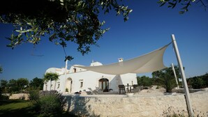 A white building with a dome, a stone wall, and a white canopy.