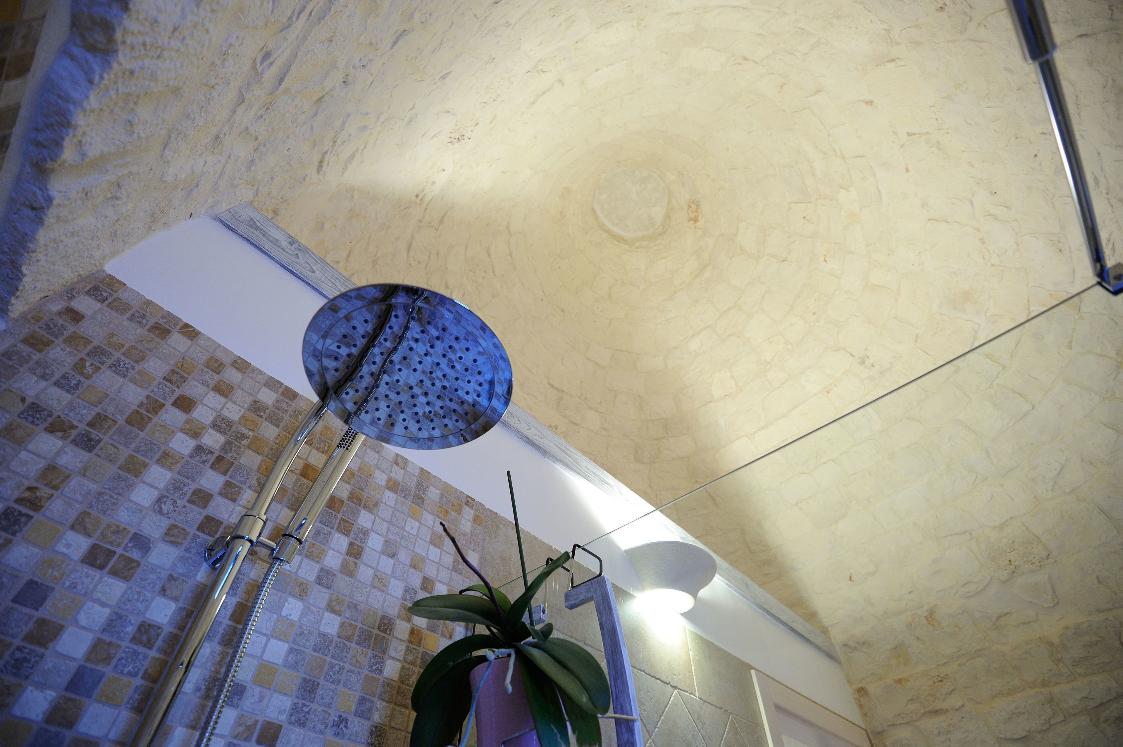 A bathroom with a tiled floor, a showerhead, and a ceiling with a textured finish.