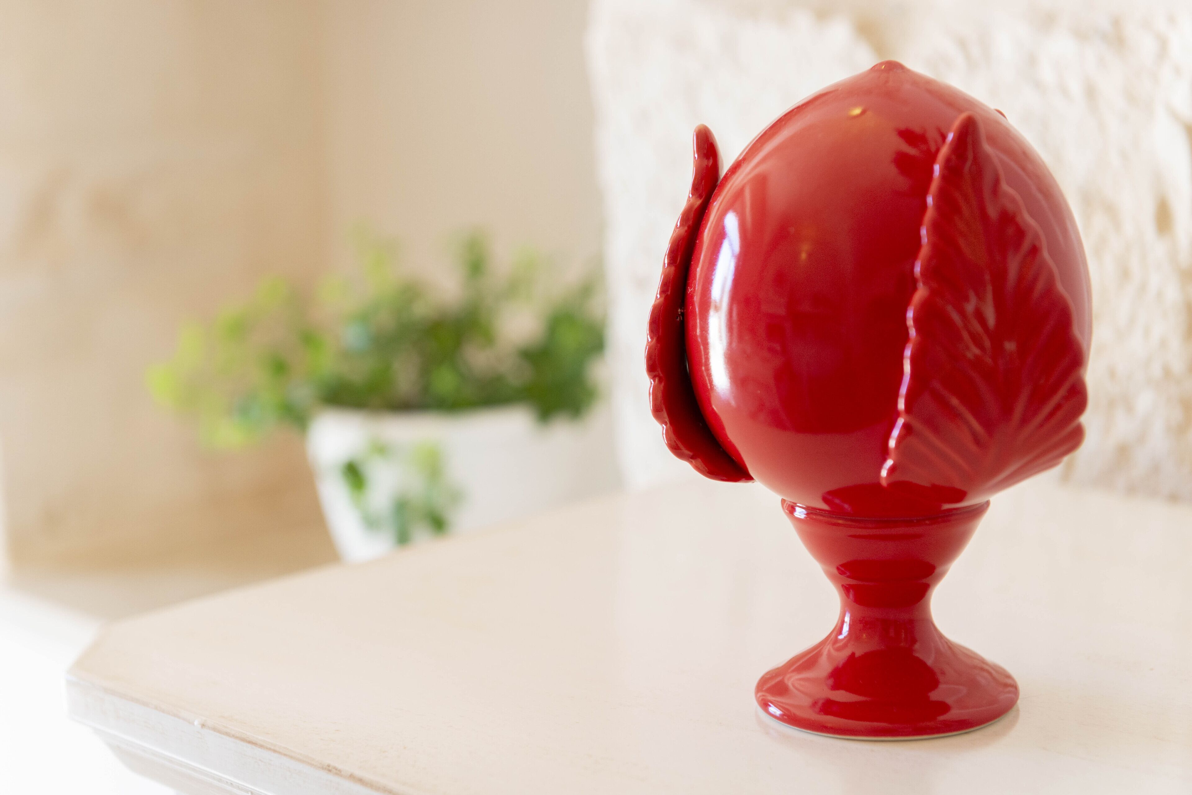 Un objeto decorativo rojo sobre una superficie blanca.