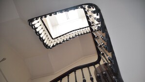 A spiral staircase with a handrail and a light fixture at the top. - The Bank Guest House (Hawick)