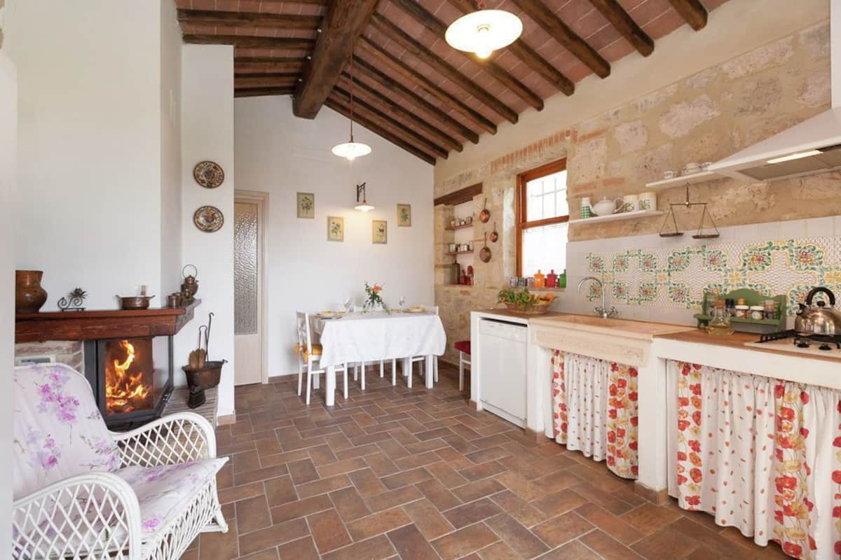 Un intérieur rustique avec une cheminée, une table à manger et un coin cuisine.