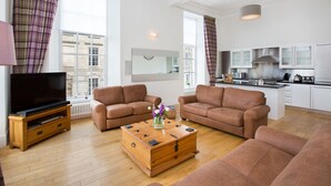 A modern living room with two brown sofas, a wooden coffee table, and a TV on a wooden stand. - Blythswood Square Apartments (Glasgow)