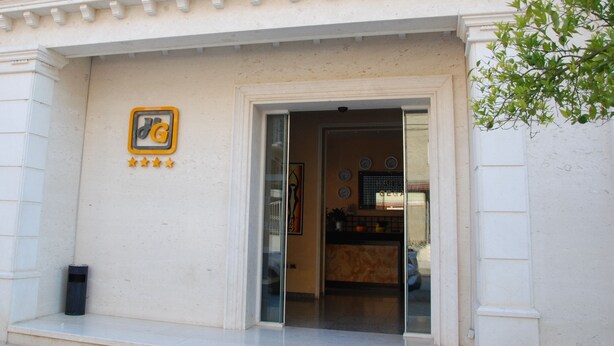 The exterior of Hotel Gega with a clear entrance, a logo with stars, and a visible clock on the wall. - Hotel Gega (Berat)