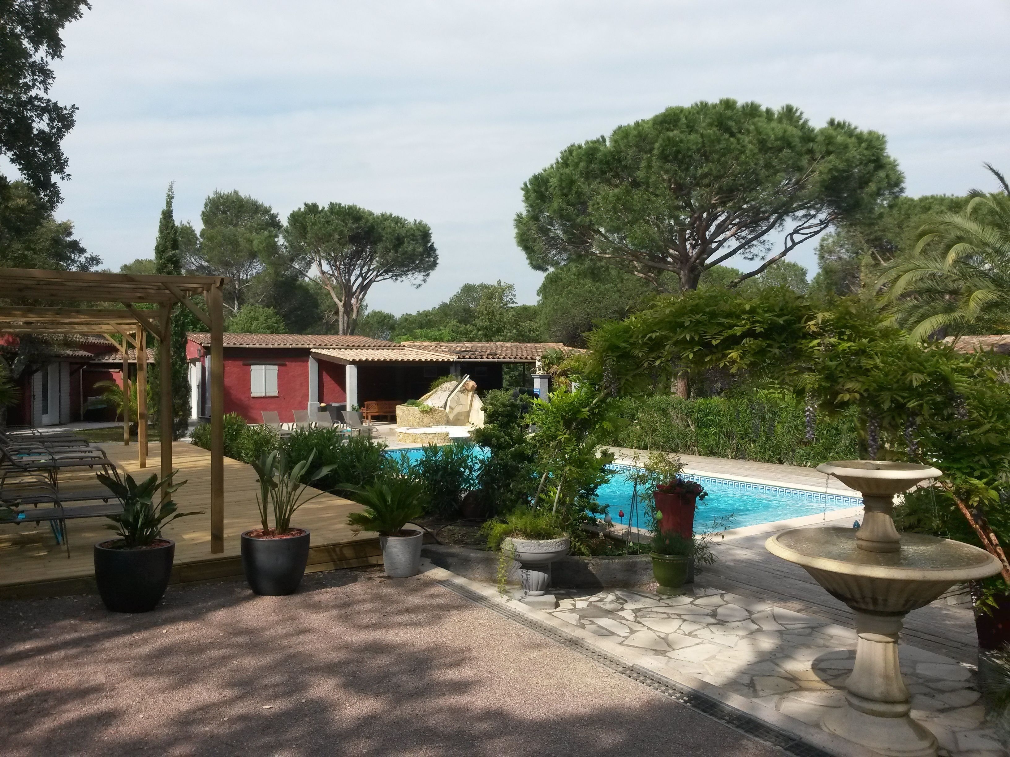 A pool area with a pergola, lounge chairs, and potted plants.