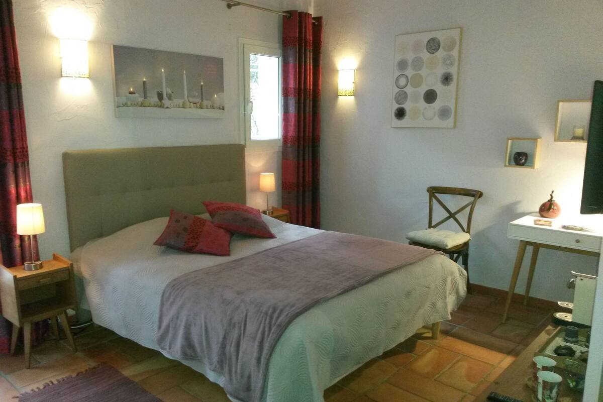 A bedroom with a bed, nightstands, a desk, and a chair.