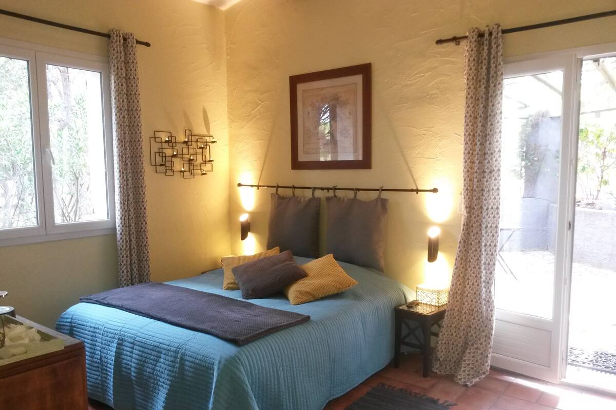 A bedroom with a bed, bedside lamps, a picture on the wall, and a window with curtains.