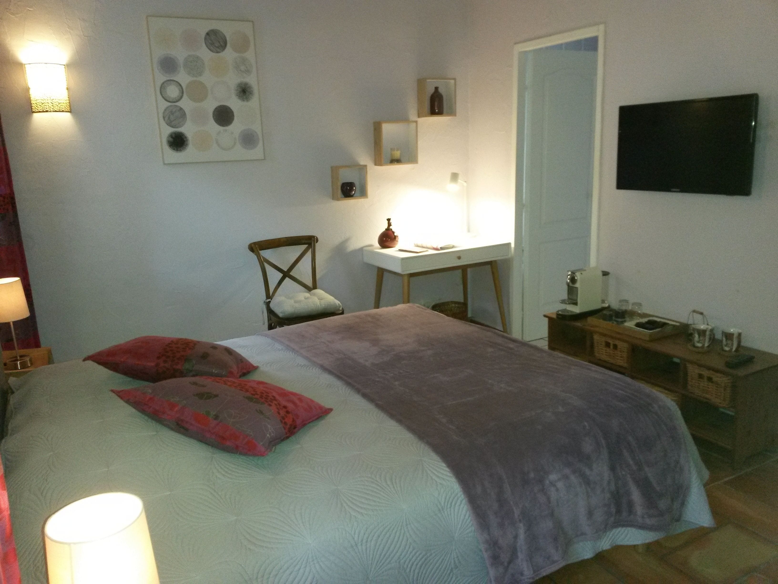Een slaapkamer met een bed, een bureau, een stoel, een televisie en een muur met een rond patroon.