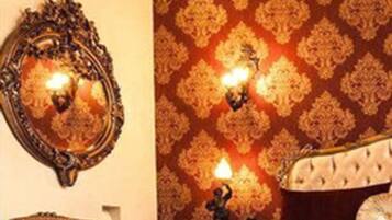 Une chambre à coucher avec un grand lit, des appliques murales décoratives, un miroir et un fauteuil rouge.