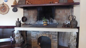 A stone fireplace with a wooden mantel, surrounded by stone walls and a wooden bench. - Rincón de Pepe (El Castell de Guadalest)