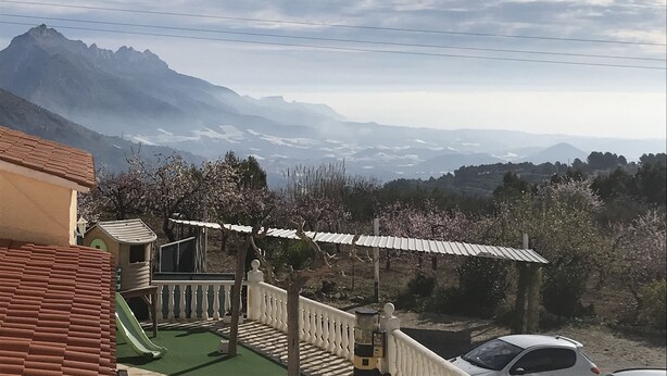 A residential area with a view of distant mountains, a playground, and a car parked nearby. - Rincón de Pepe (El Castell de Guadalest)