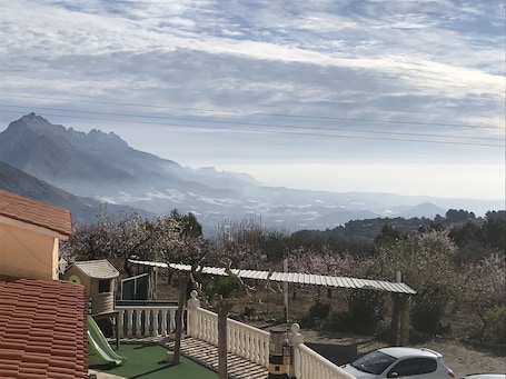 A residential area with a view of distant mountains, a playground, and a car parked nearby.