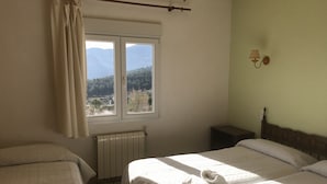 A bedroom with two beds, a window with a view of mountains, a radiator, and a nightstand. - Rincón de Pepe (El Castell de Guadalest)
