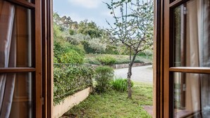 A view through an open window with a brick pathway leading to a grassy area and a body of water. - Tenuta degli Obizzi (Montecarlo)