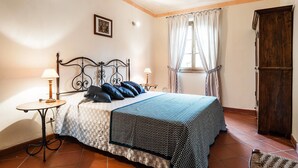 A bedroom with a bed, two bedside tables, a window with curtains, a door, and a wall-mounted picture. - Tenuta degli Obizzi (Montecarlo)
