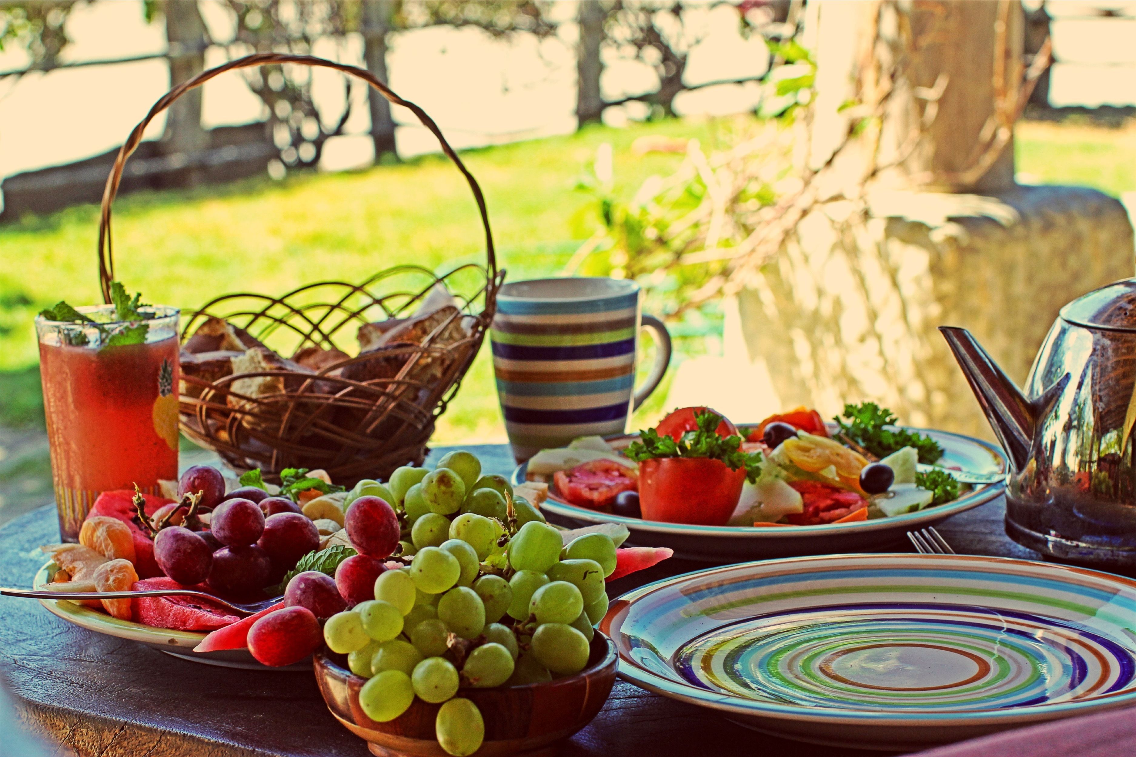A table set with a variety of fruits, a pitcher, and a striped mug.