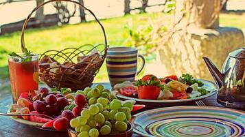 A table set with a variety of fruits, a pitcher, and a striped mug.