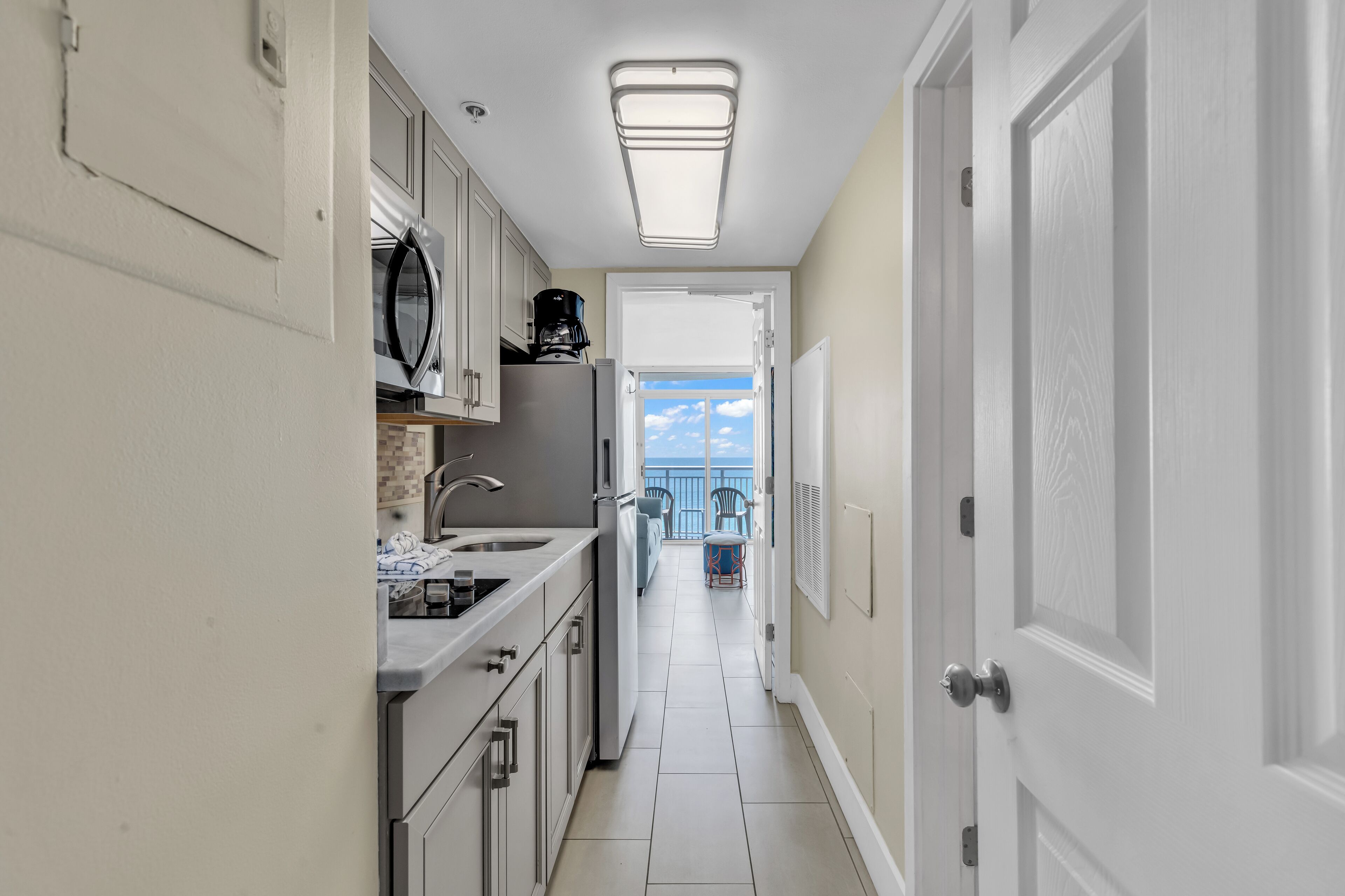 A narrow kitchen with a view to a balcony.