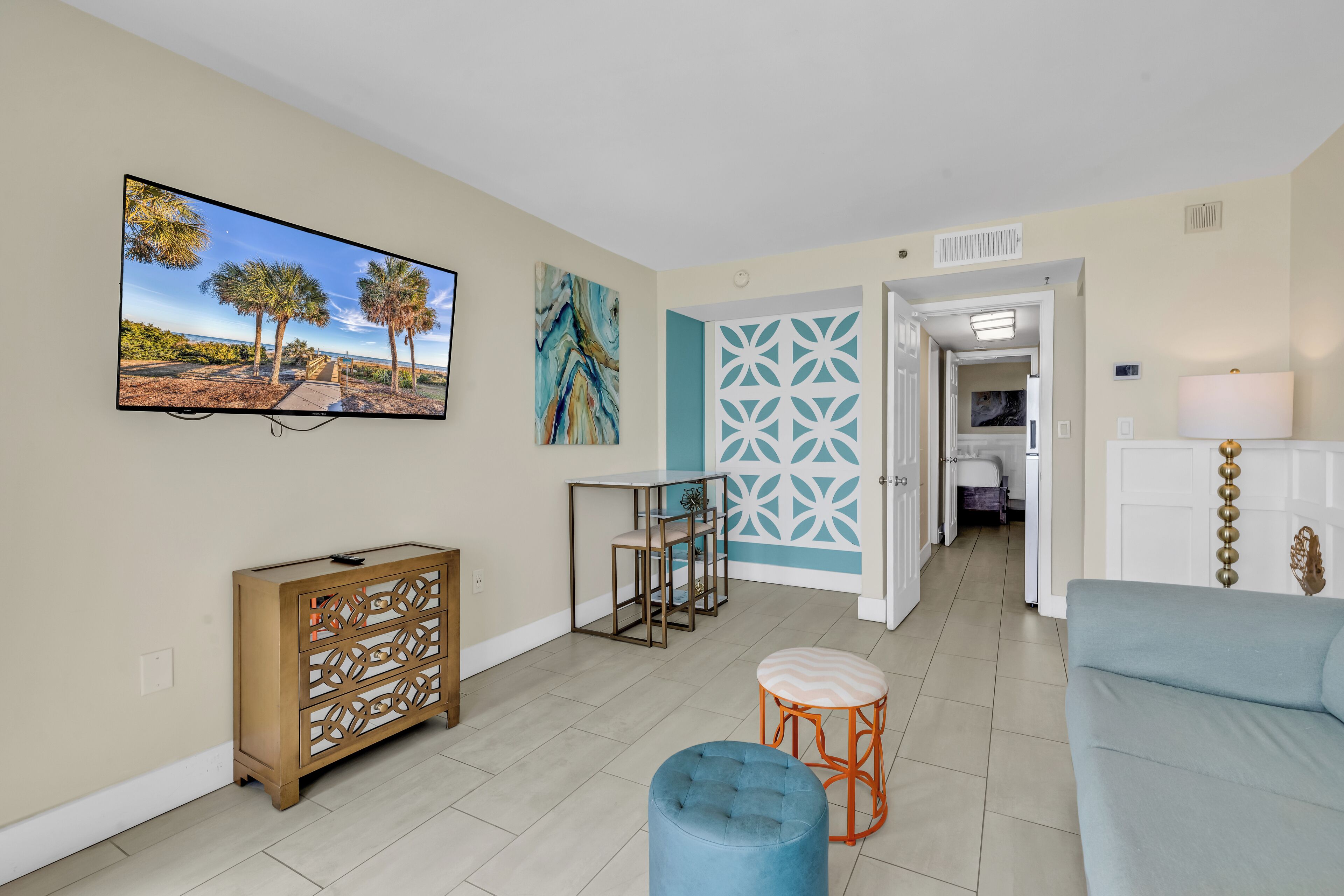 Un salon comprenant un téléviseur, un canapé, une table basse et un panneau décoratif mural.