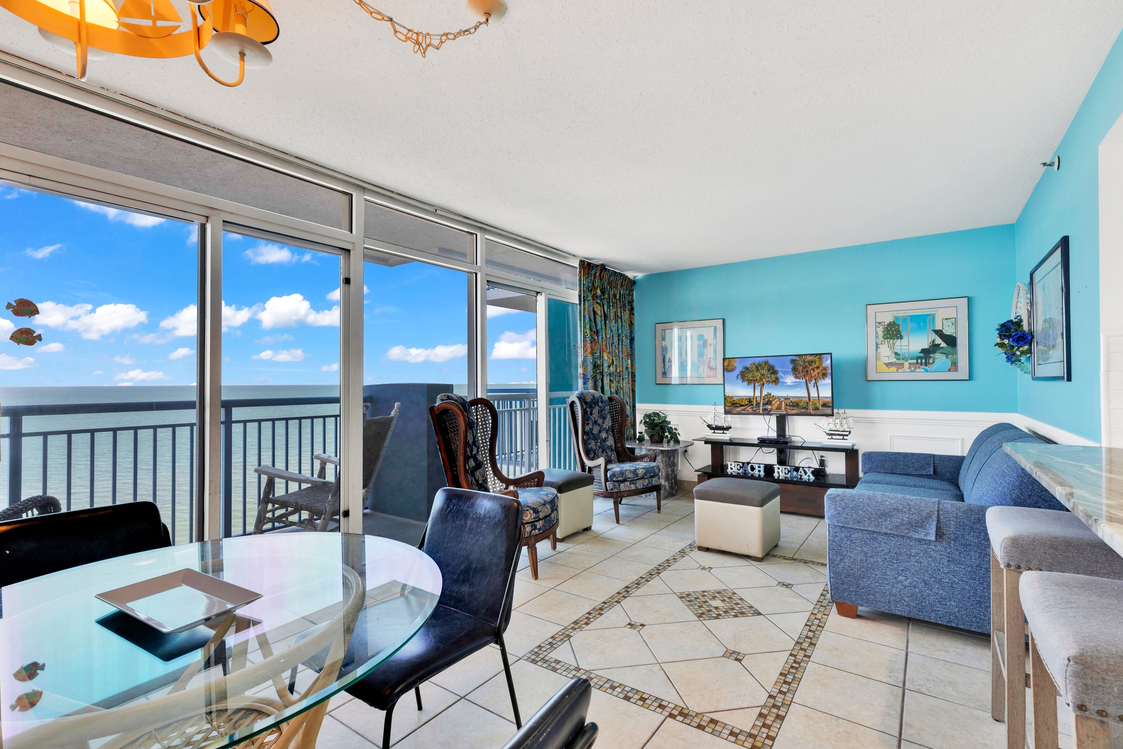 A spacious living room with a balcony, a glass table, and a sofa.