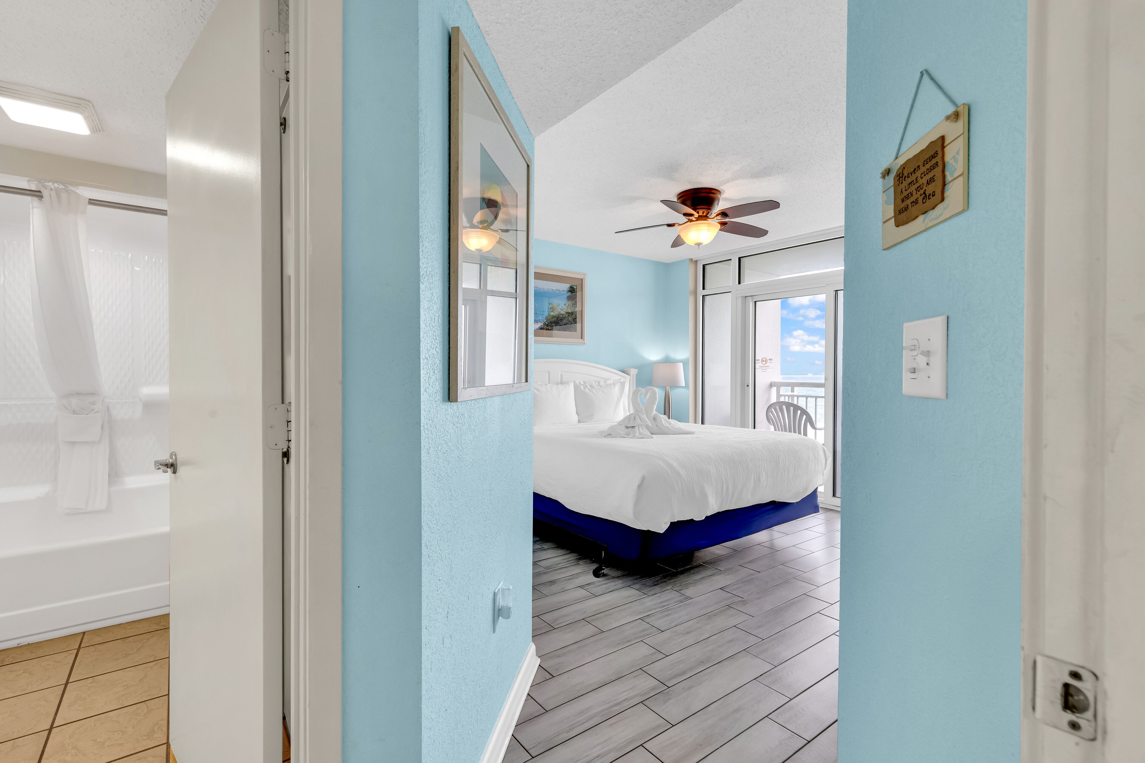 A bedroom with a bed, a ceiling fan, a window, and a view of the outside.