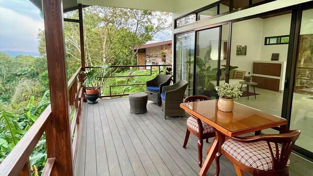 Um deck de madeira com mesa e cadeiras, com vista para uma paisagem exuberante.