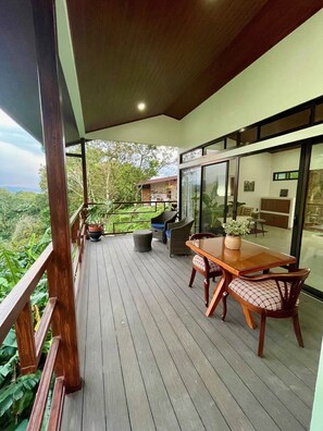 Une terrasse en bois avec une table et des chaises, offrant une vue sur un paysage luxuriant.