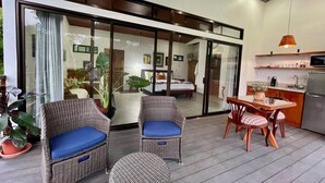 Um espaço de estar moderno com móveis de vime, uma mesa de jantar e uma cozinha.