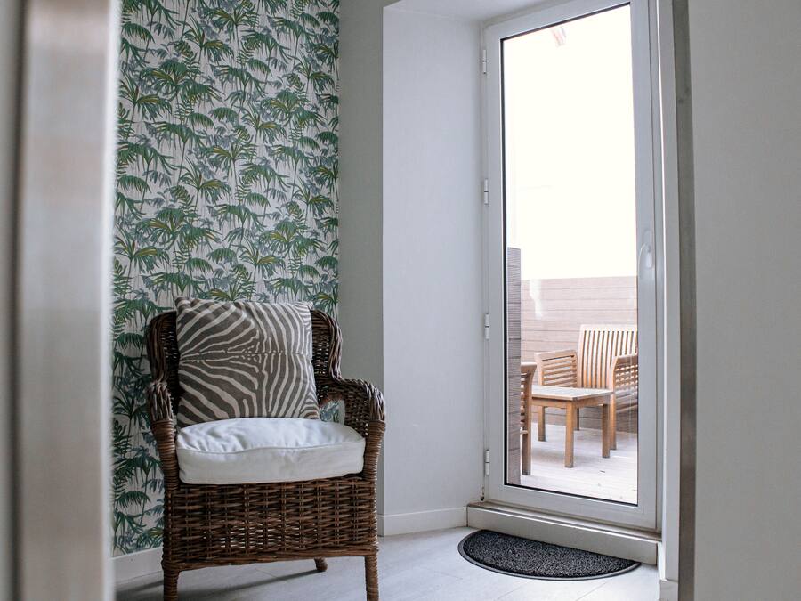 A wicker chair with a cushion and a patterned wall.