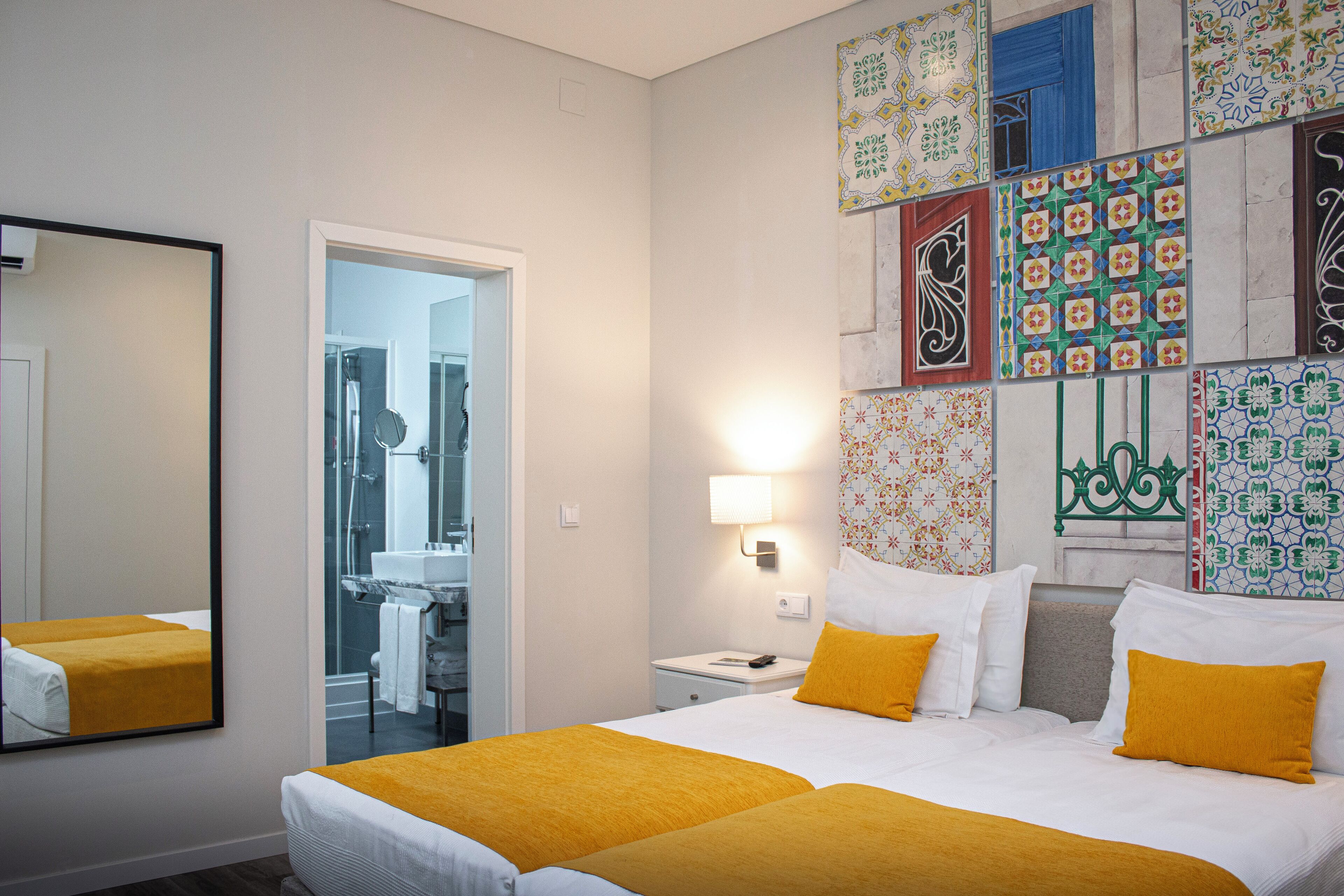 Een hotelkamer met twee bedden, een grote spiegel en een douche.