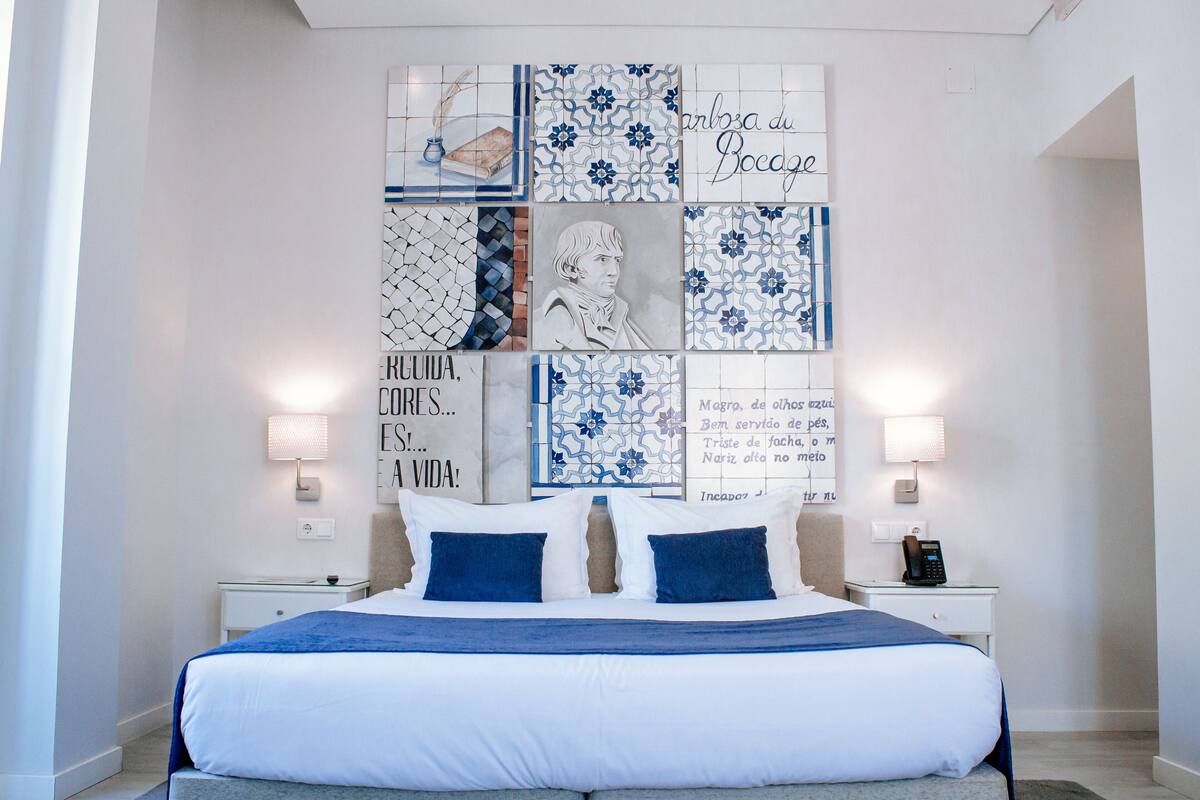 A bedroom with a large bed, two bedside tables, and a wall decorated with blue and white tiles.