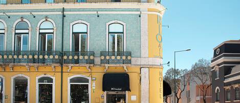 A hotel with a yellow facade, multiple windows, and a black awning.