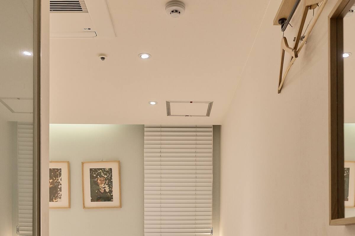 Een slaapkamer met twee bedden, een houten hoofdeinde, kunst aan de muur en een raam met zonwering.