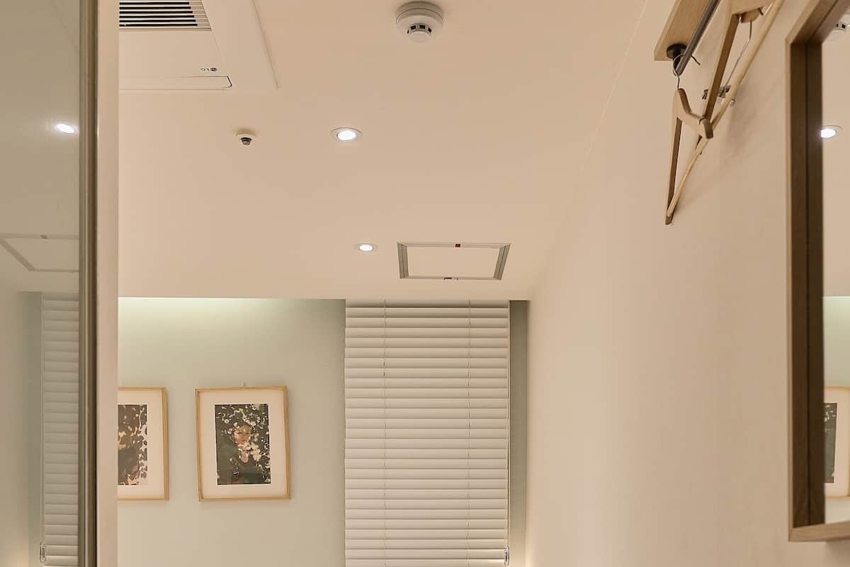 A bedroom with two beds, a wooden headboard, wall-mounted artwork, and a window with blinds.