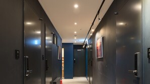 Een moderne hal met donkere wanden, inbouwverlichting en een vloerbedekking.